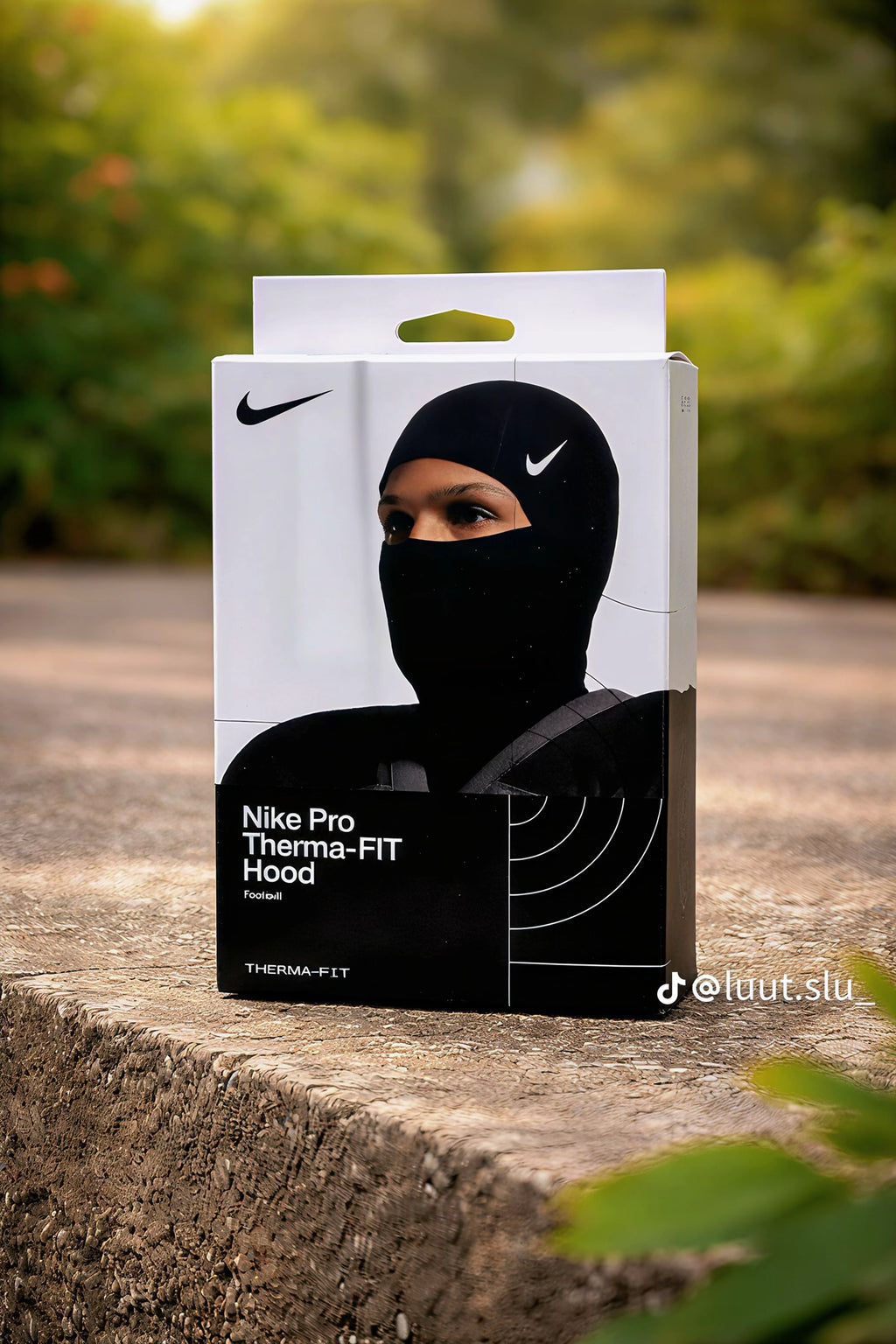 Box of Nike Pro Therma-FIT Hood on a stone surface with blurred greenery in the background