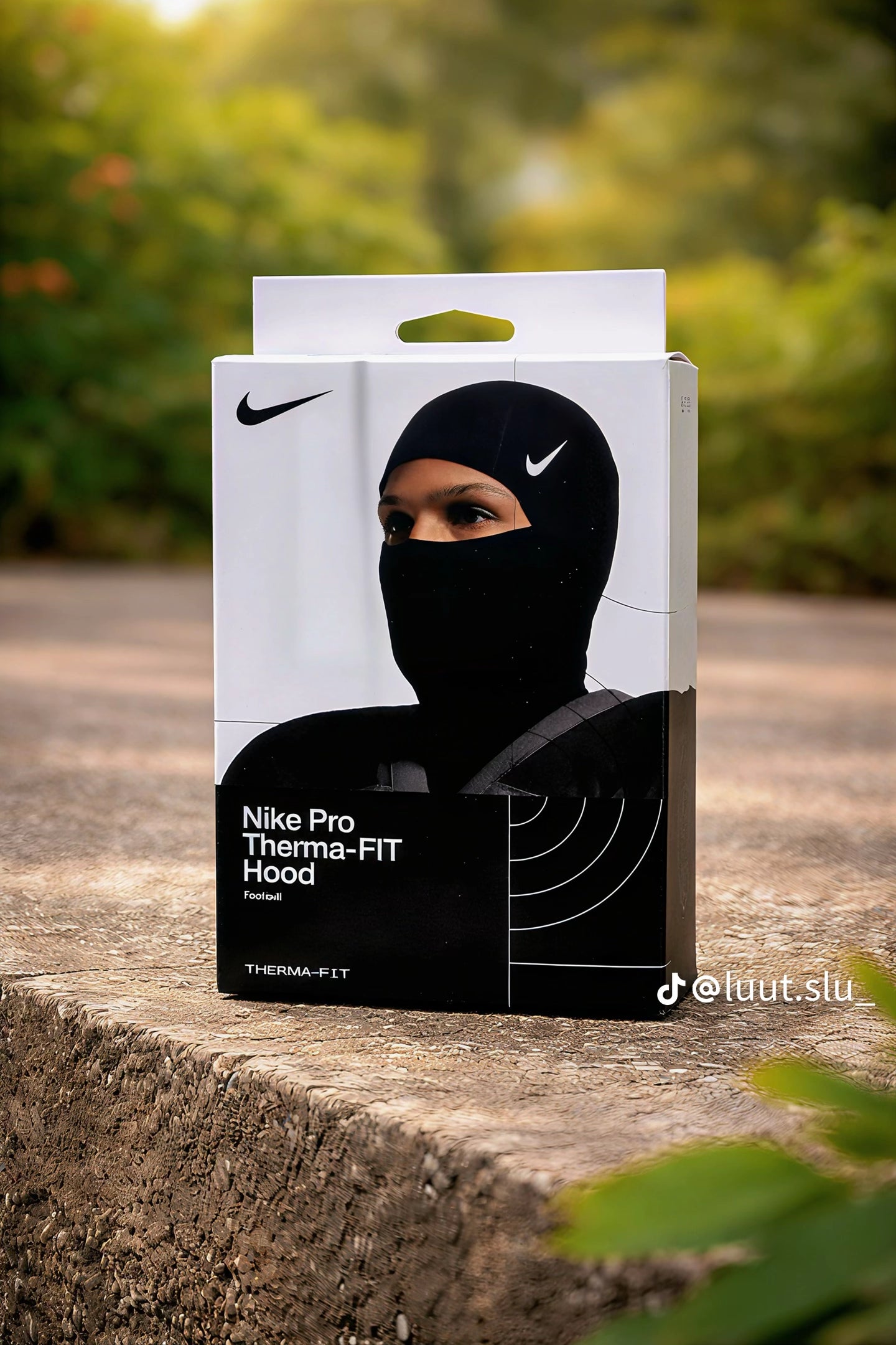Box of Nike Pro Therma-FIT Hood on a stone surface with blurred greenery in the background