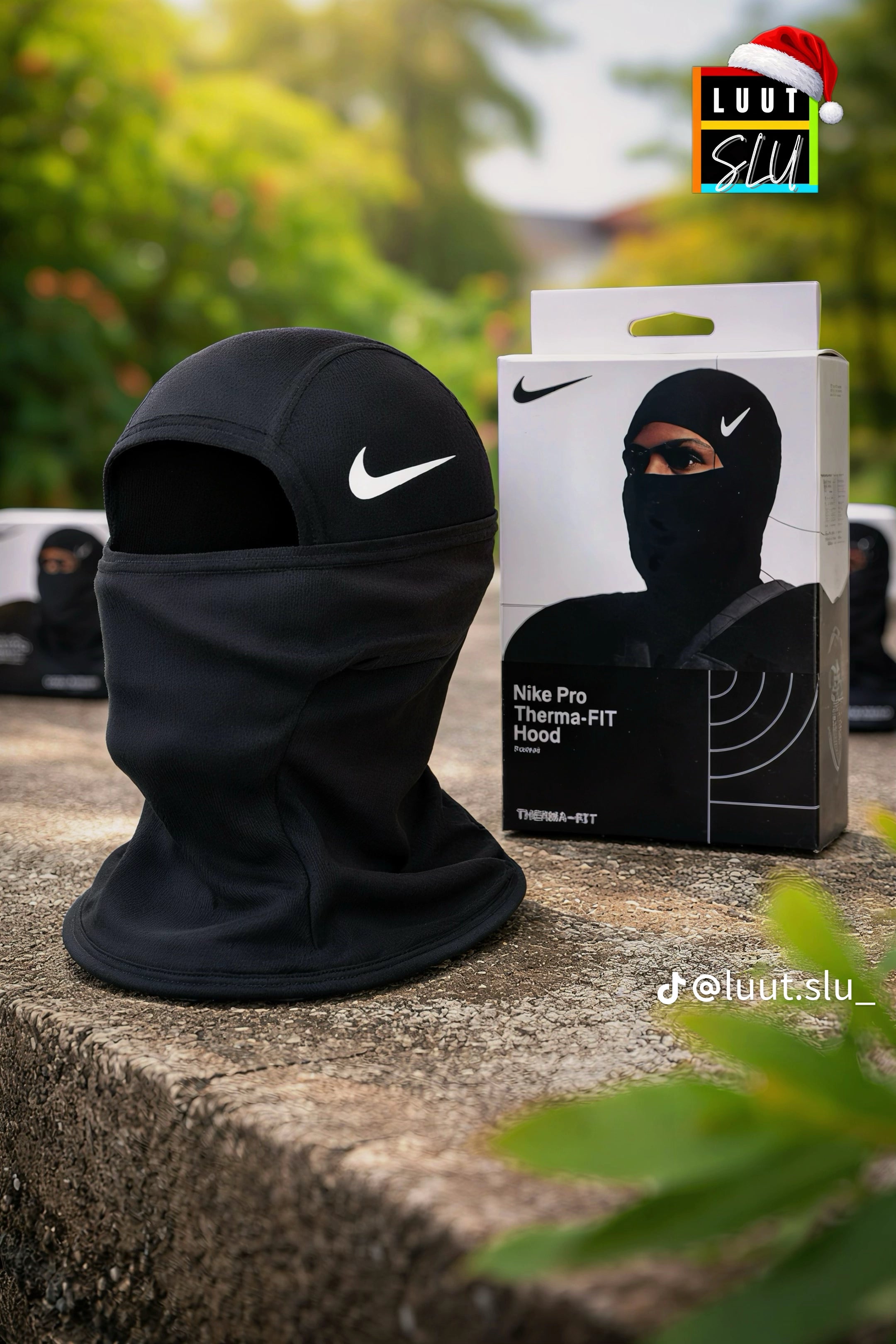 Black Nike balaclava with packaging on a stone surface with greenery in the background
